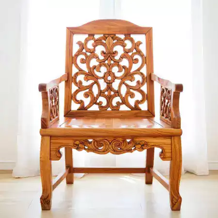 Statement rosewood armchair with elephant motif carved into high backrest and geometric patterns on armrests weighing twenty eight kilograms priced forty two thousand